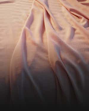 Pink hyperlite sheets draped on a Nova Hybrid Snow mattress. 